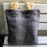 Front of fabric bag with cream color hanger on the bench