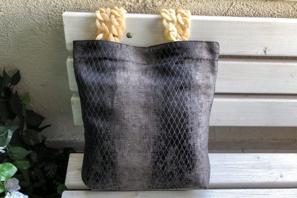 Front of fabric bag with cream color hanger on the bench