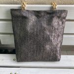 Front of the black herringbone design textured bag on the bench