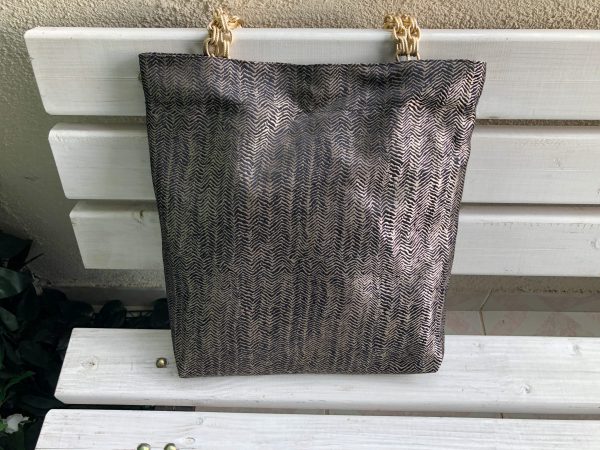 Front of the black herringbone design textured bag on the bench